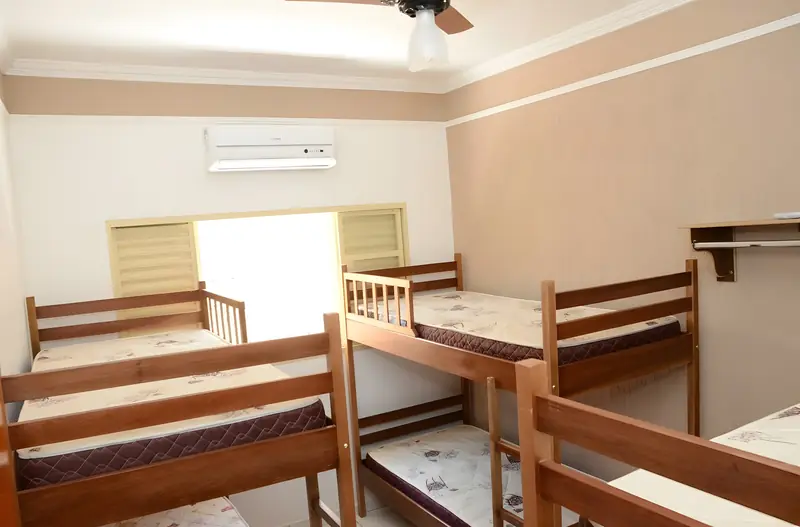 Suíte com camas e beliches de madeira, ar-condicionado e ventilador de teto