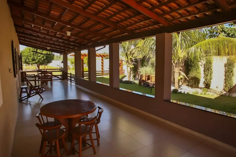 Varanda com mesa redonda de madeira, cadeiras e vista para o jardim